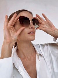 a woman in a white shirt with sunglasses on her face