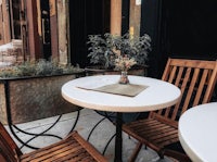 two wooden chairs and a table on a sidewalk