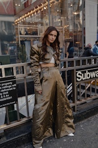 a woman in gold pants standing on a street in nyc