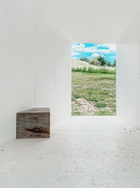 a white room with a wooden bench and a view of a field