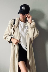 a woman wearing a trench coat and a yankees hat