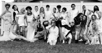 a group of people posing in front of a fence