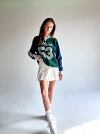 a woman wearing a green and white sweater and white shorts