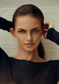 a woman in a black top posing with her hands on her head