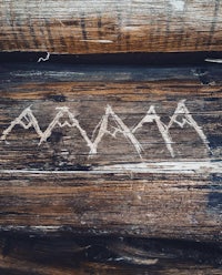 a wooden log with mountains drawn on it