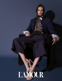a model in a suit sits on a chair