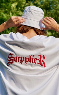 a woman wearing a white t - shirt with the word supplyk on it