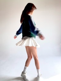 a woman in a white skirt and white sneakers