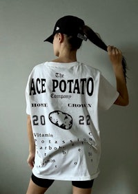 a woman wearing a white ace potato t - shirt